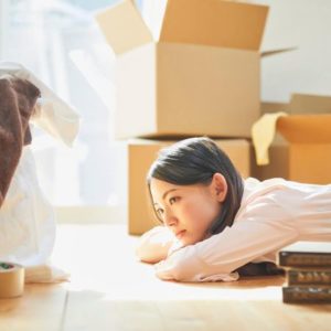 引っ越しの段ボールがある部屋でうつ伏せている女性