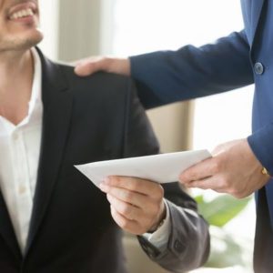 上司から封筒を手渡されたスーツ姿の男性