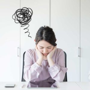 両手で頬杖をついて目を閉じてうつむく女性