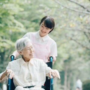 車椅子に座る高齢女性と、車椅子を押す介護士の女性