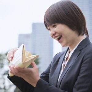 笑顔で財布の中を除く、スーツ姿の若い女性